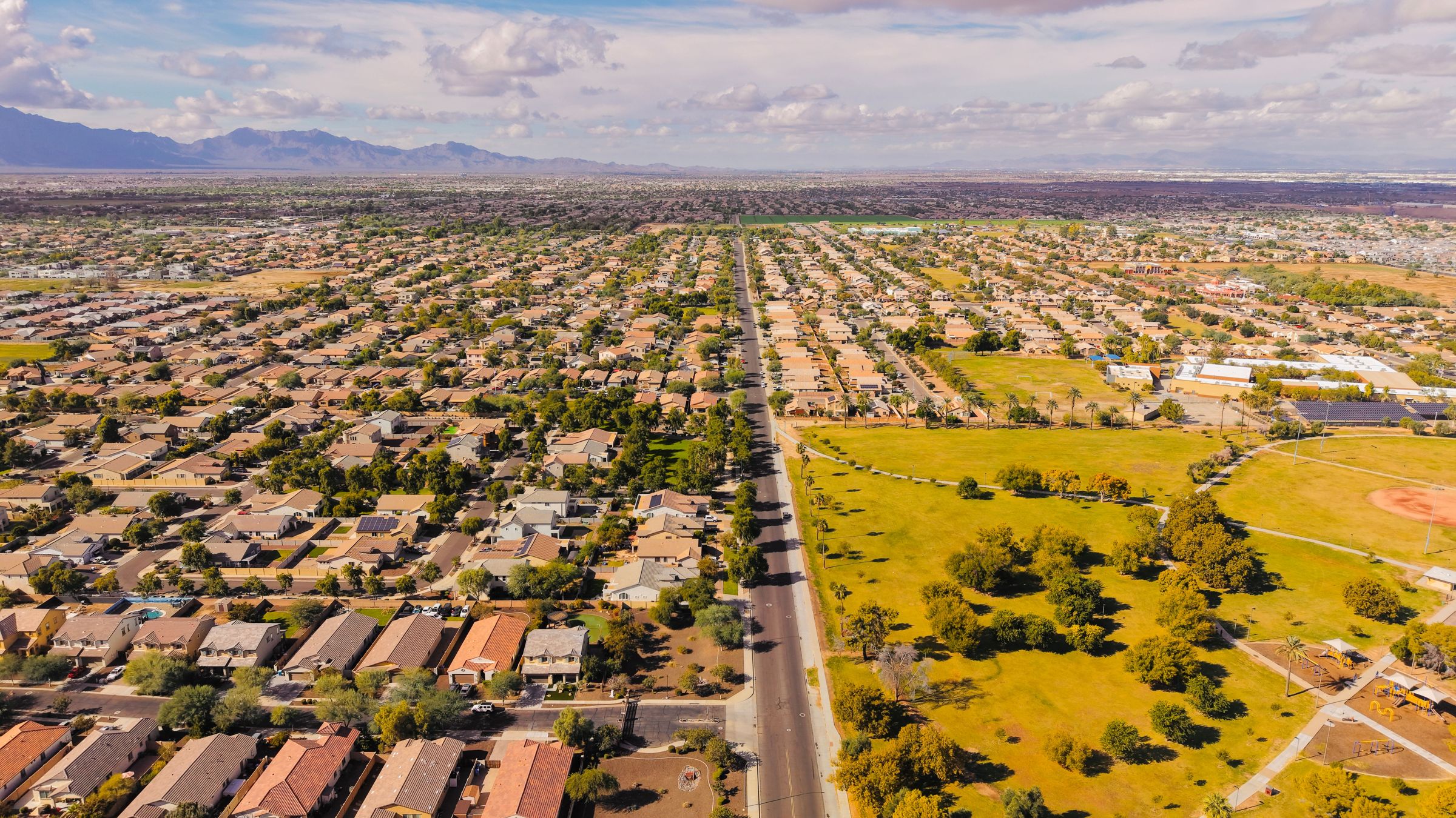 Aerial view of a sunny Phoenix-area neighborhood with mountains on the horizon